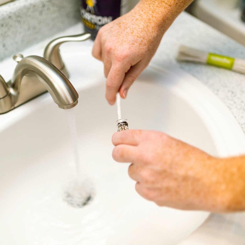 person holding silver steel faucet